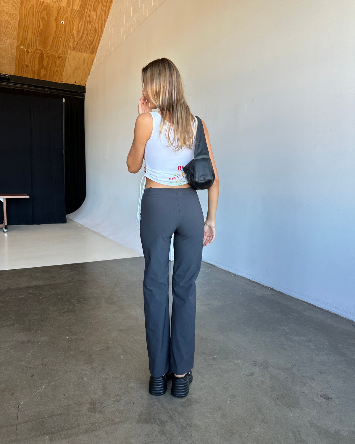 model:S/8AU H:171CM 
Charcoal Capsule Pants, back view, worn with a white sleeveless top.
