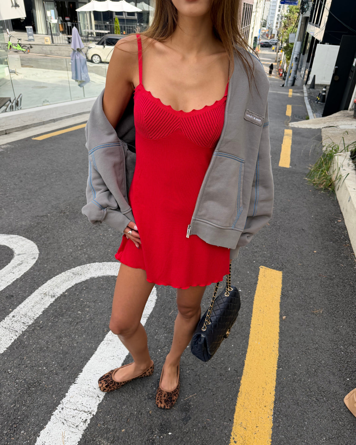 model:XS/6AU
Front view of the red Ribbed Knit Dress worn with a grey cardigan, showing the scalloped neckline, fitted bust and flared skirt.