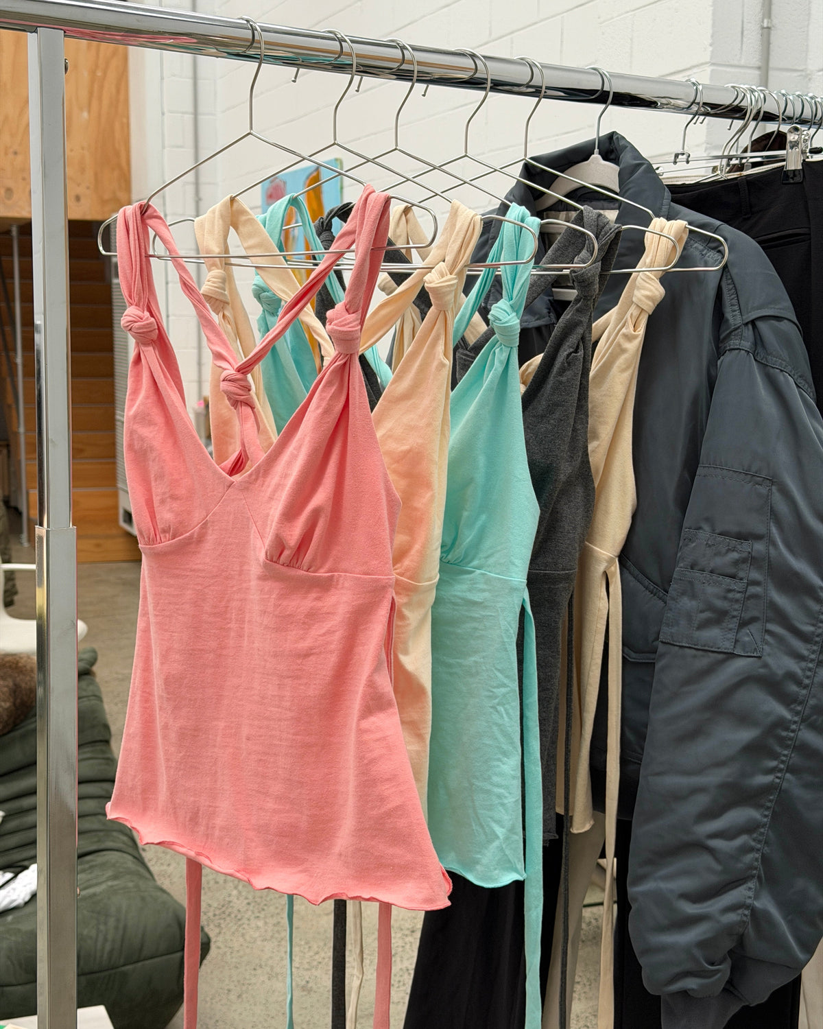 Peach Bailee Knot Tank, hanging on a rail beside other colourways.