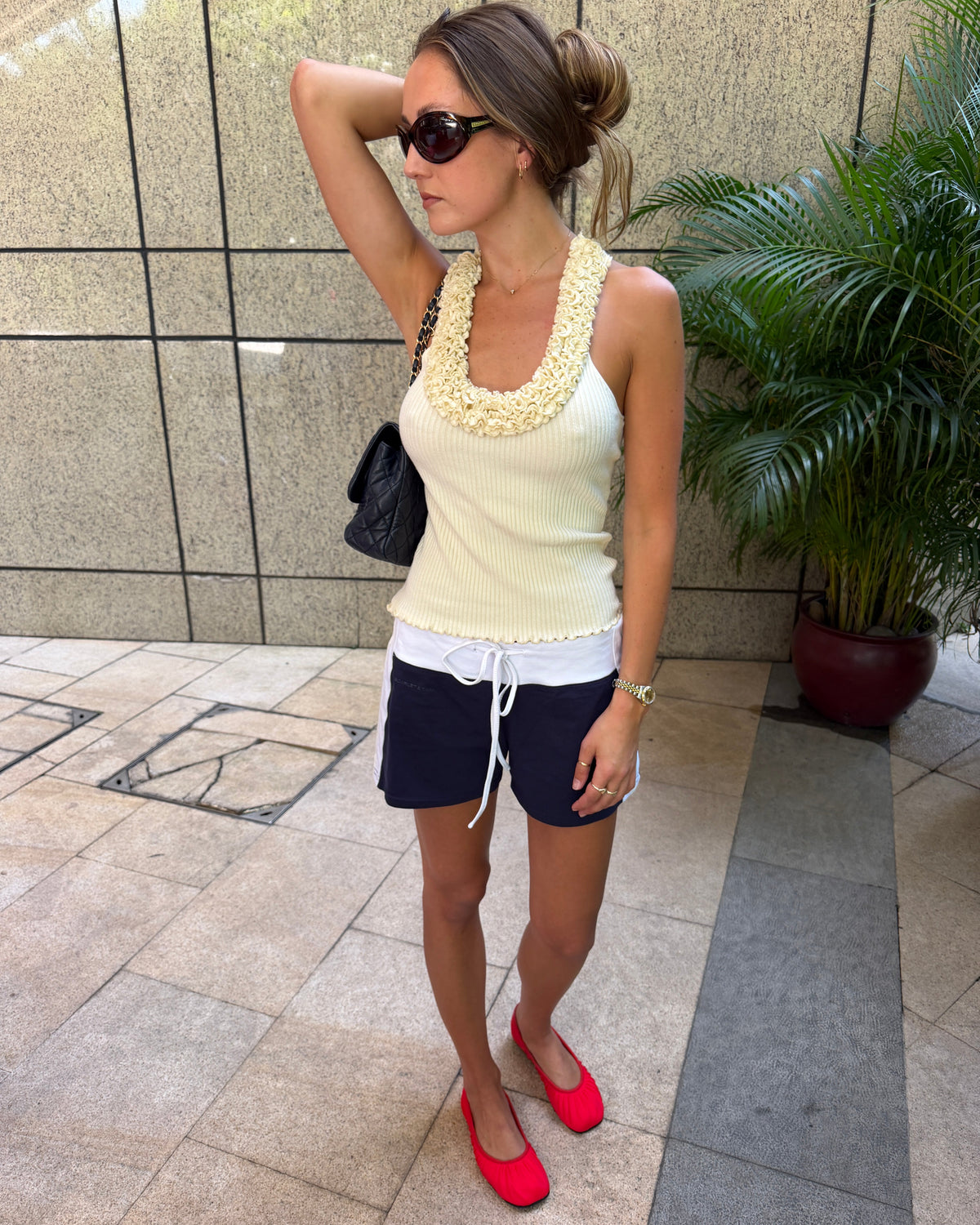 model:S/8AU H:173CM
Cream Ruffle Knit Tank, front view, showing the ruffled scoop neckline, ribbed knit and scalloped hem, styled with navy shorts and red ballet flats.
