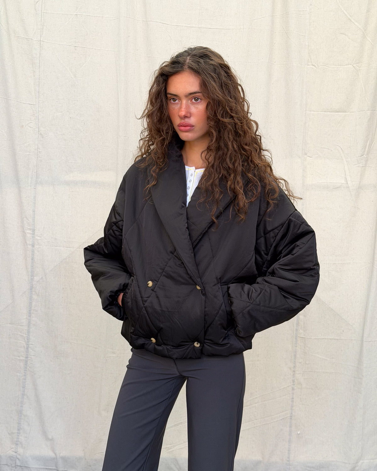 model:XS/6AU H:179CM 
Black Cocoon Padded Jacket, angled front view, showing the rounded padded shape and dropped shoulders.