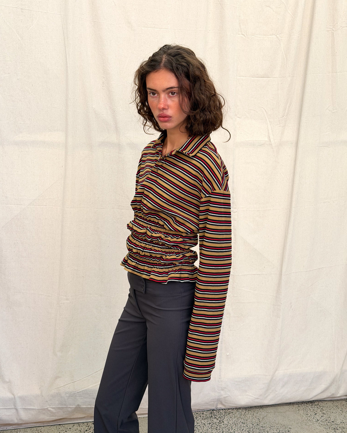 model:XS/6AU H:179CM 
Mustard stripe Eden Rugby Polo, angled front view, showing the dropped shoulder, long sleeve and gathered waist.