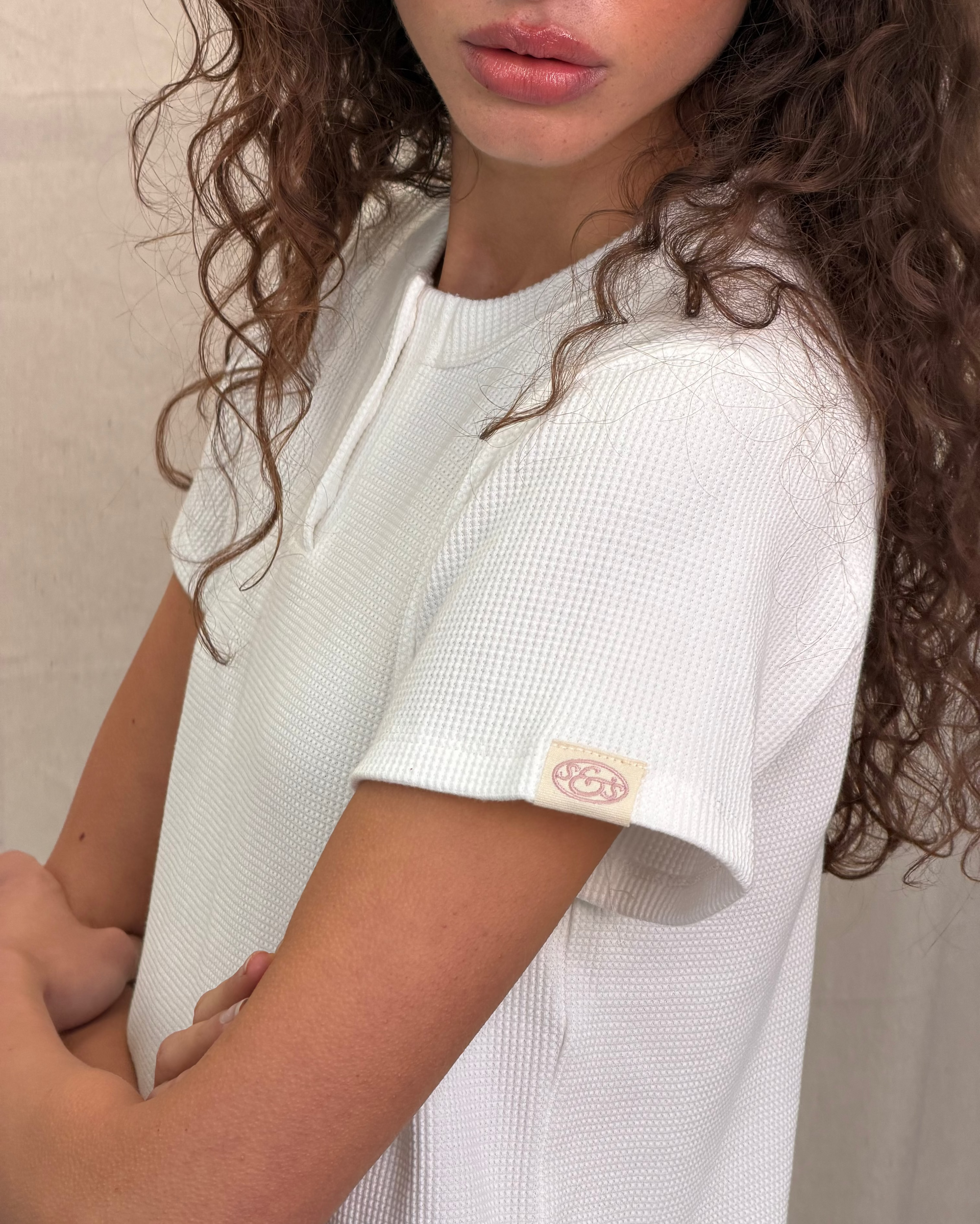 model:S/8AU H:179CM 
Scarlet & Sam white Waffle Tee close-up showing textured waffle fabric and the embroidered logo tab on the sleeve.