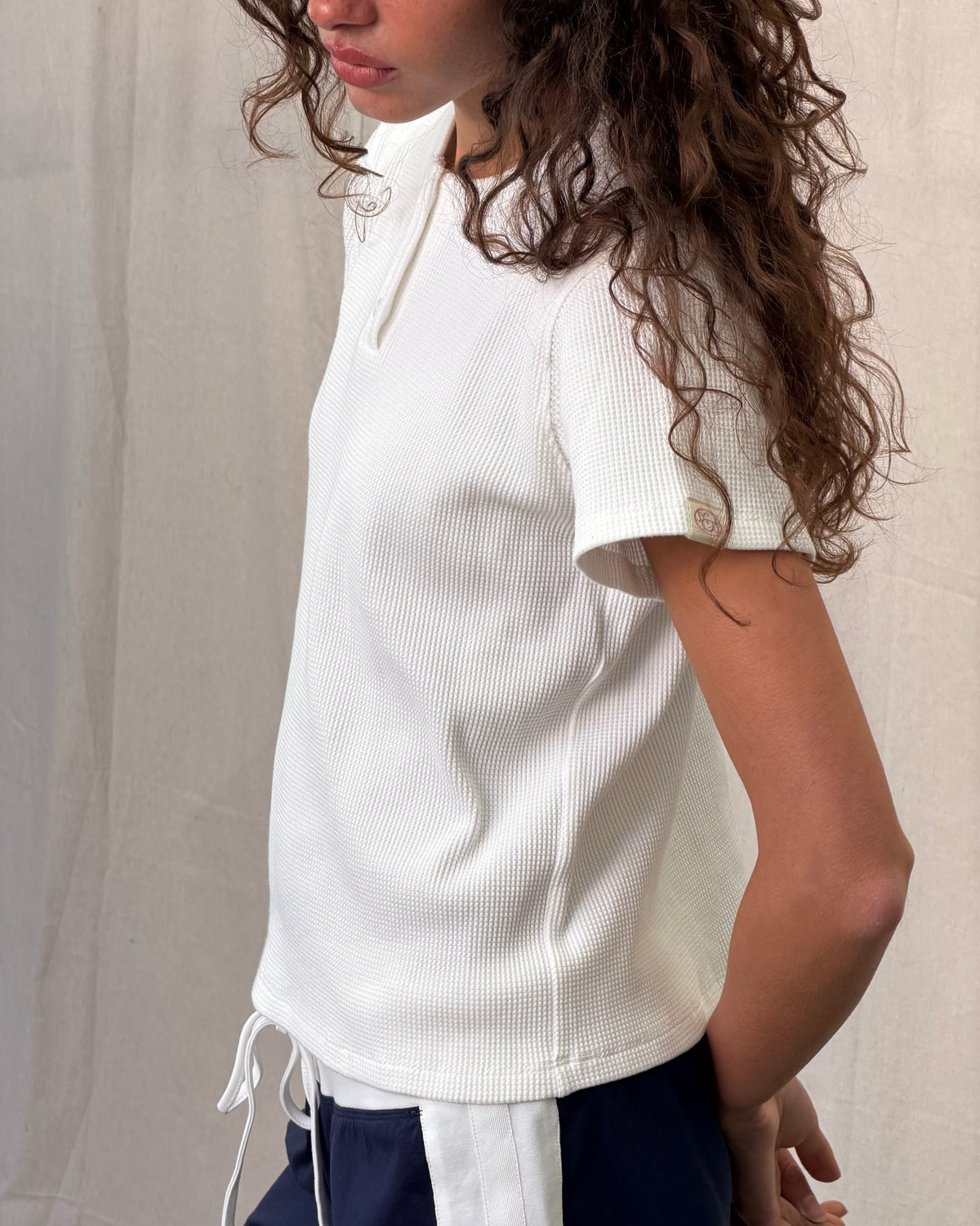 model:S/8AU H:179CM 
Scarlet & Sam white Waffle Tee styled on a model with black trousers and a tan shoulder bag.