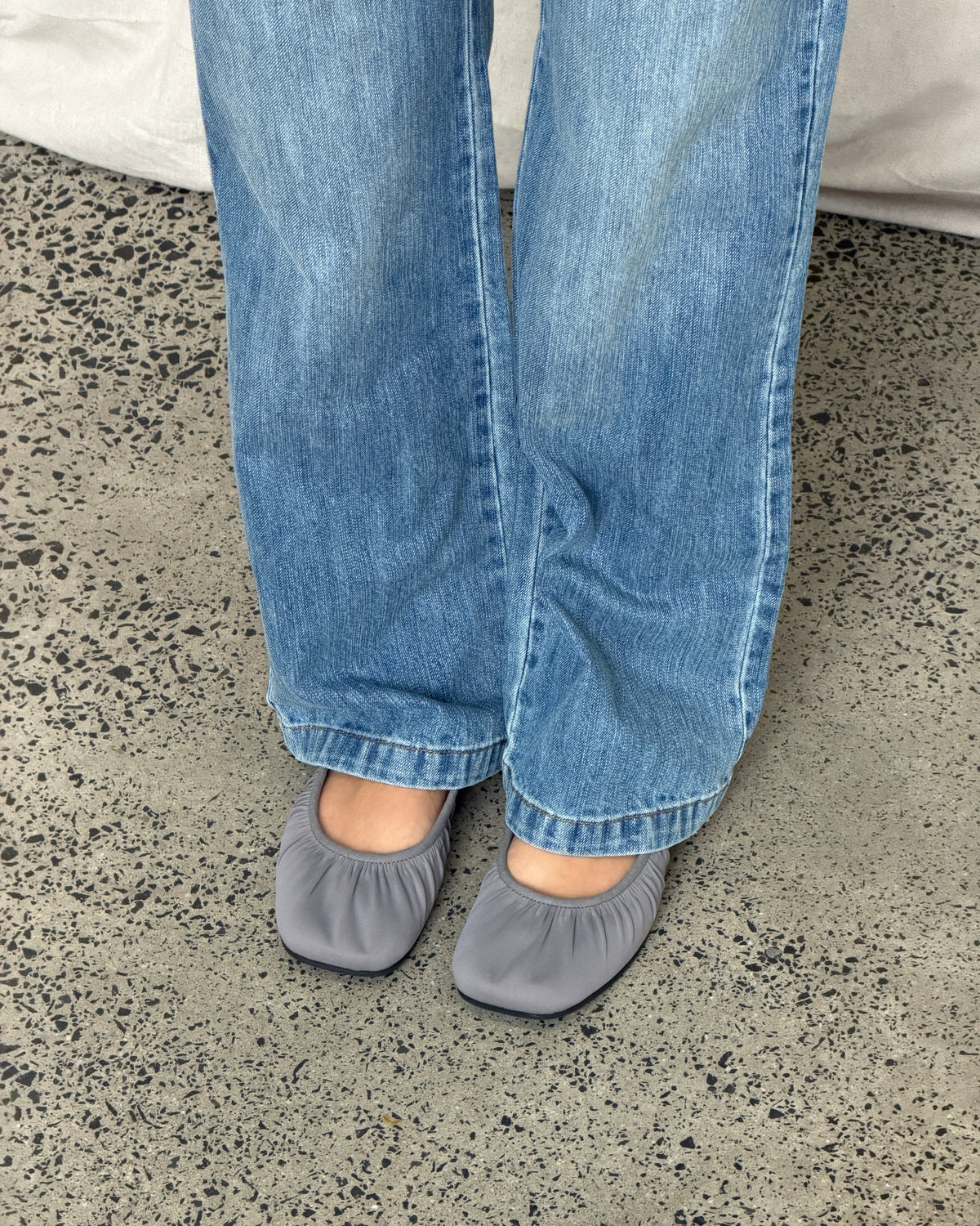 Grey Noa Neoprene Ballet Flat, close view on feet beneath blue jeans.