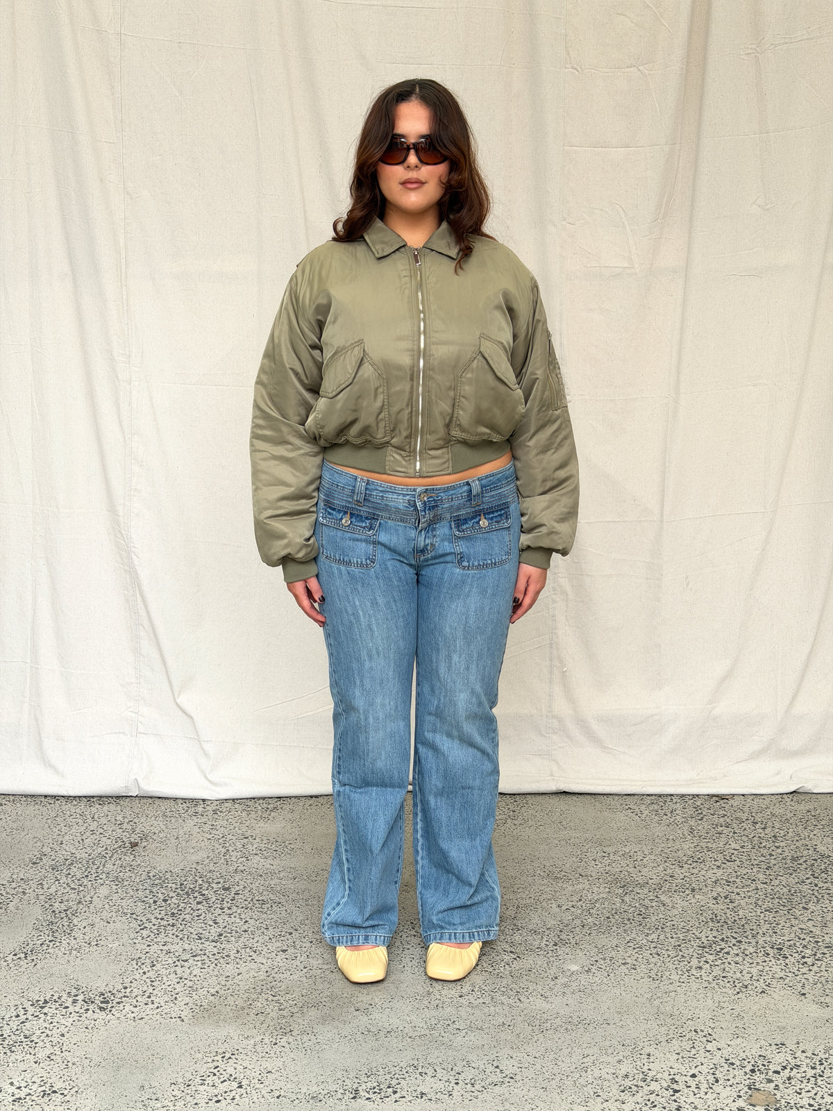 model:L/XL/12-16AU H:173CM 
Khaki Capsule Bomber, front view, zipped up with blue jeans.