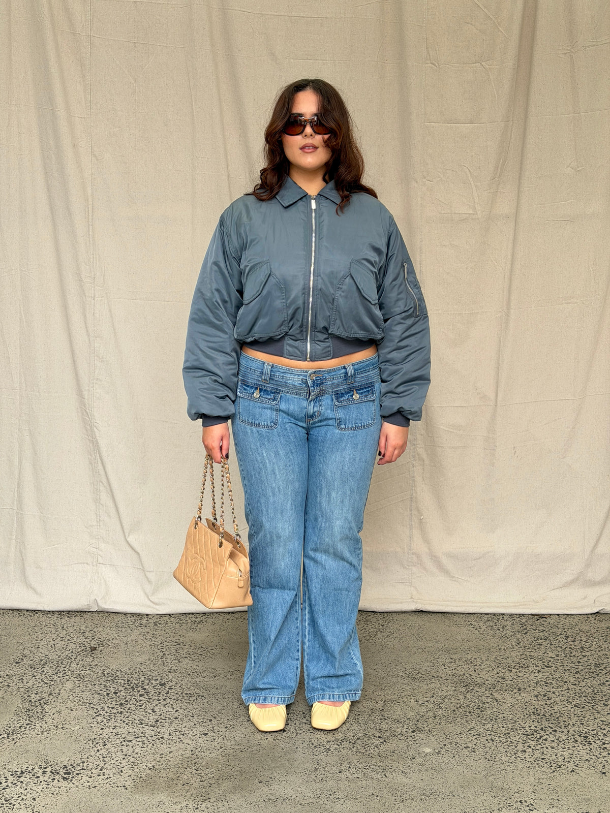model:XL/14-16AU H:173CM 
Blue 90s Low Rise Jeans, full-length styling view with a charcoal bomber.