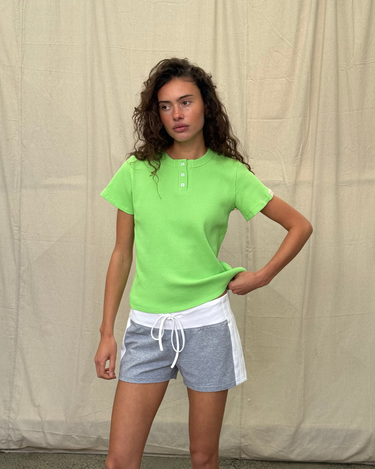 model:S/8AU H:179CM 
Scarlet & Sam lime Waffle Tee, side view on a model looking towards the camera, showing the relaxed fit and sleeve tab.