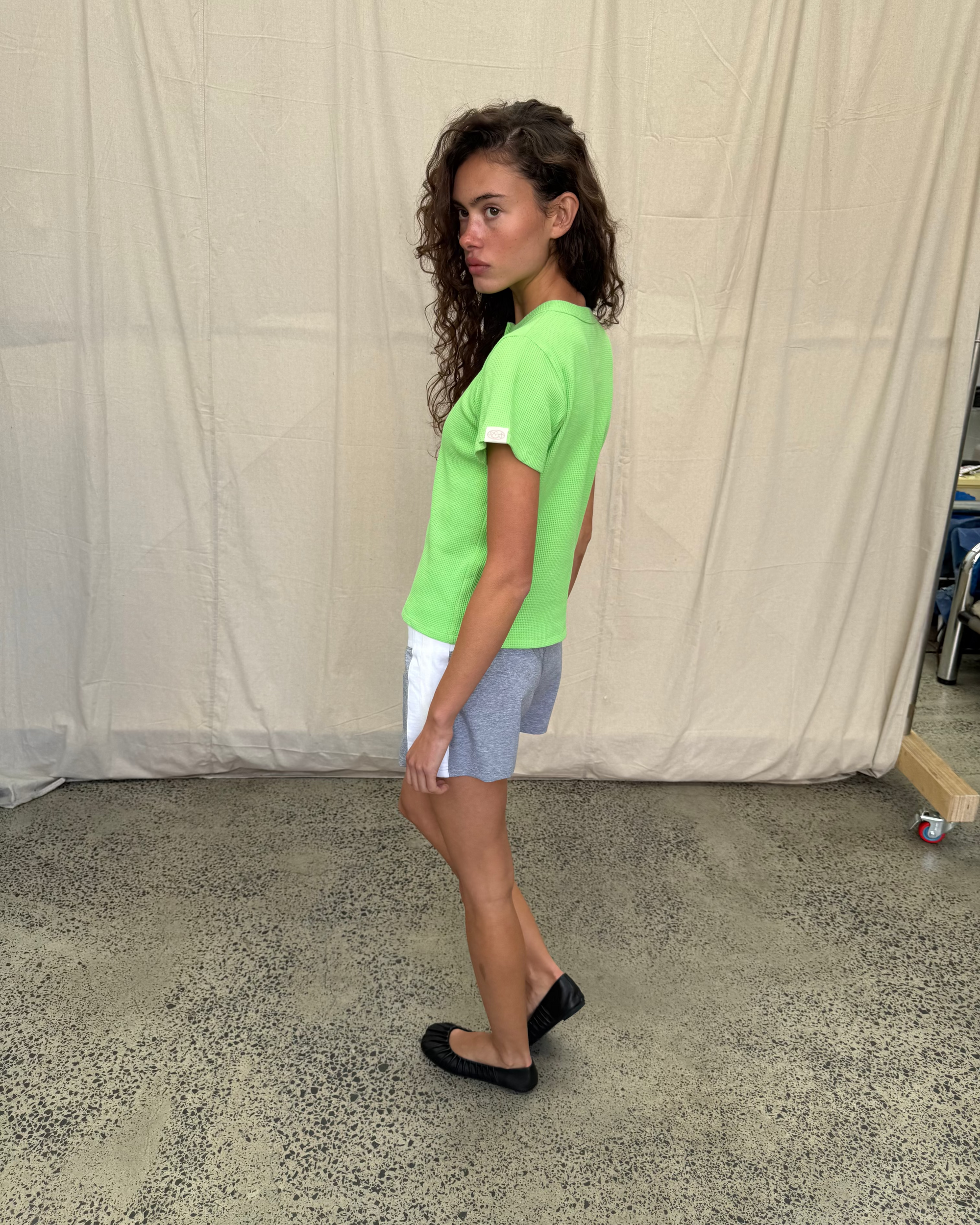 model:S/8AU H:179CM 
Scarlet & Sam lime Waffle Tee, full-length side view on a model wearing grey shorts and black flats.