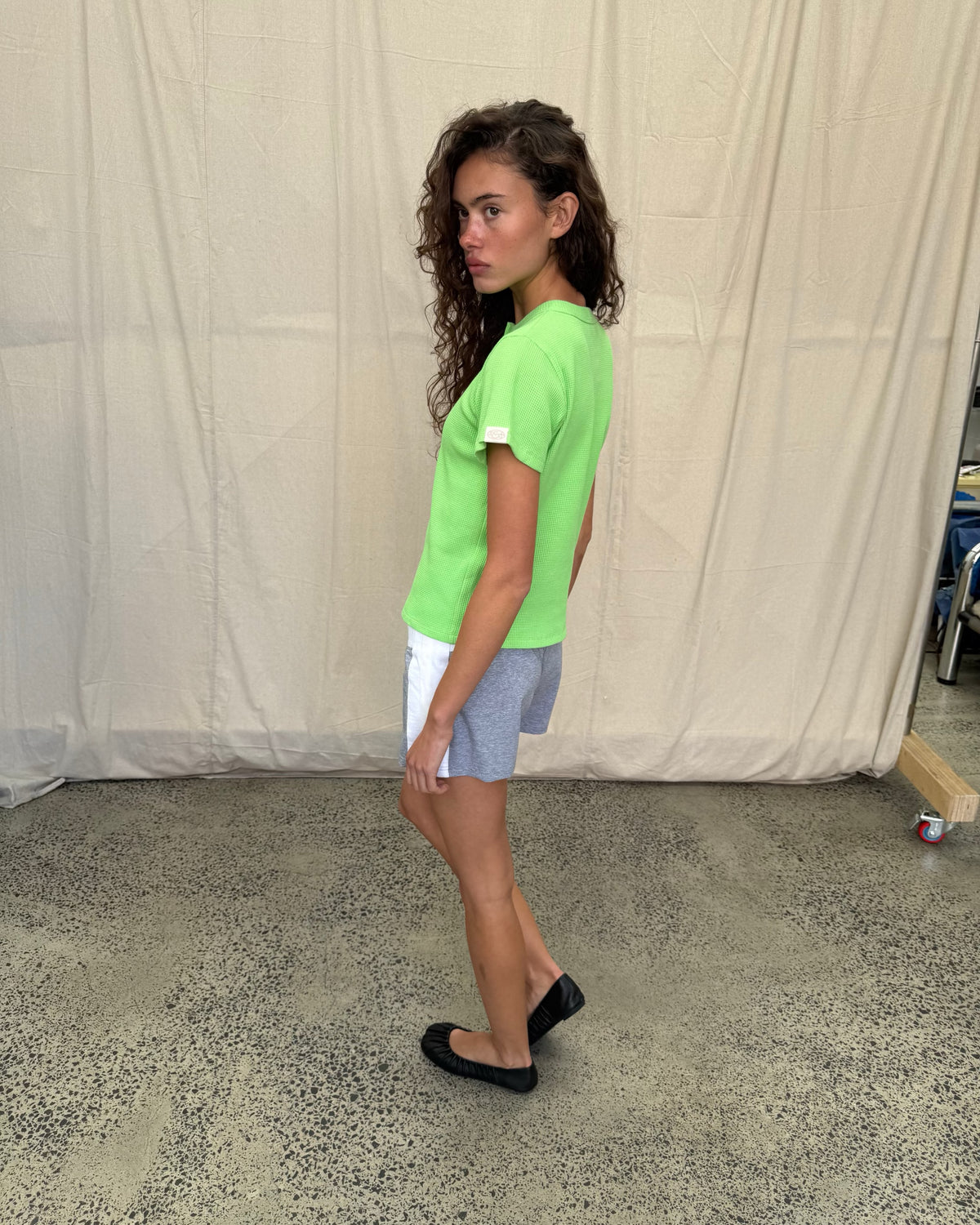 model:S/8AU H:179CM 
Scarlet & Sam apple green Waffle Tee, side view on a model looking towards the camera, showing the relaxed fit and sleeve tab.