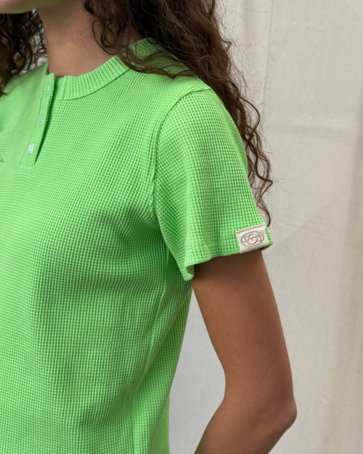 model:S/8AU H:179CM 
Scarlet & Sam apple green Waffle Tee, side view on a model looking towards the camera, showing the relaxed fit and sleeve tab.