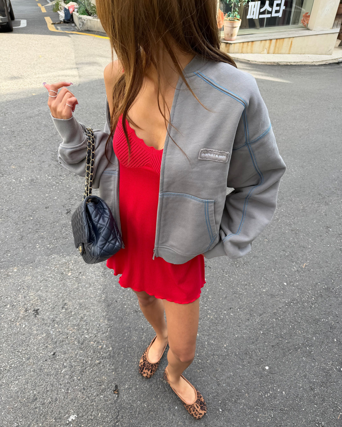 model:S/6-8AU
Grey Capsule Stitch Cardigan worn open over a red Ribbed Knit Dress, showing the oversized fit, contrast stitching and patch pockets.