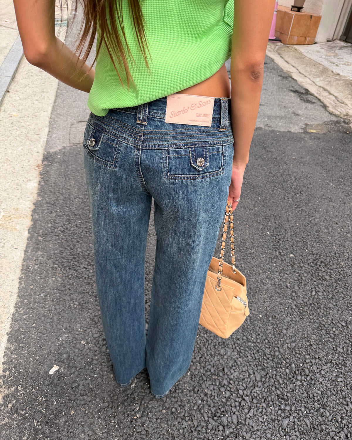 model:XS/6AU
Back detail of the vintage blue 90s Low Rise Jeans, showing buttoned patch pockets, contrast stitching and the pink waistband label.
