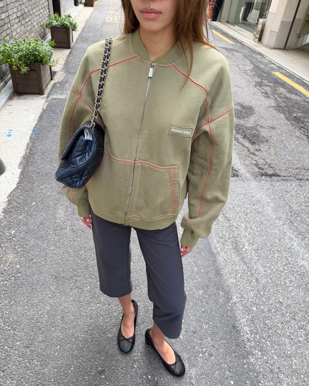model:S/6-8AU
Front view of the khaki Capsule Stitch Cardigan zipped up, showing contrast stitching, patch pockets and a ribbed neckline.