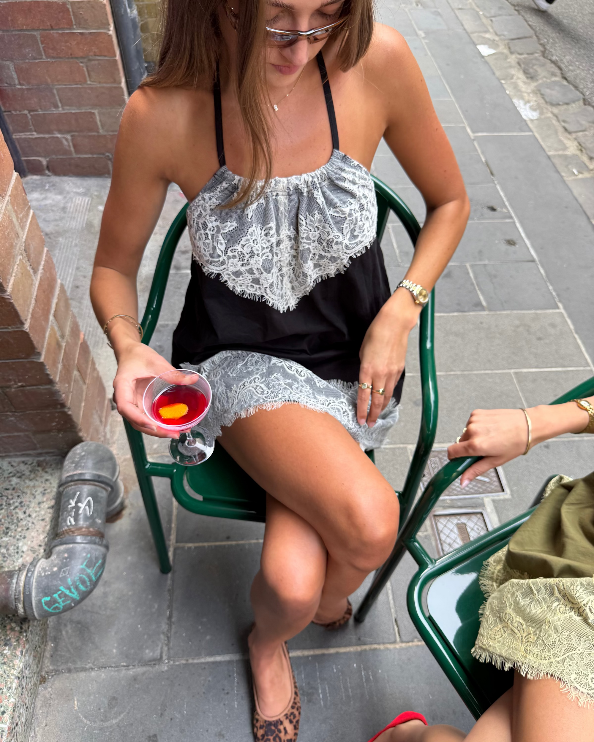 model:S/8AU H:173CM 
Black Jersey Lace Halter Dress worn seated outdoors, showing the gathered lace neckline, relaxed shape and contrast lace hem.