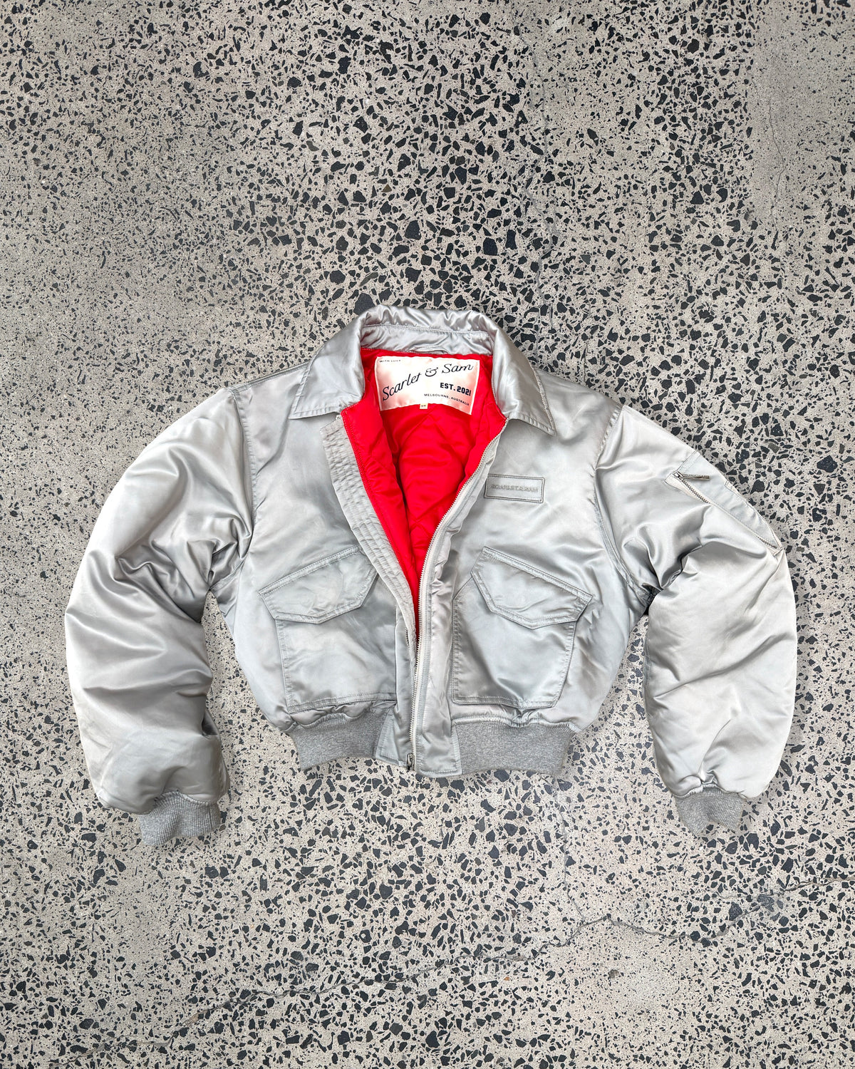 Silver Capsule Bomber, laid flat with red lining visible.