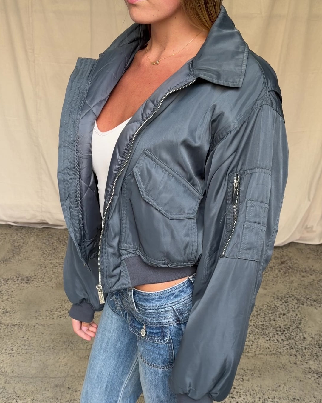 Video preview: Charcoal Capsule Bomber, worn open, showing the front pockets and sleeve zip pocket.
